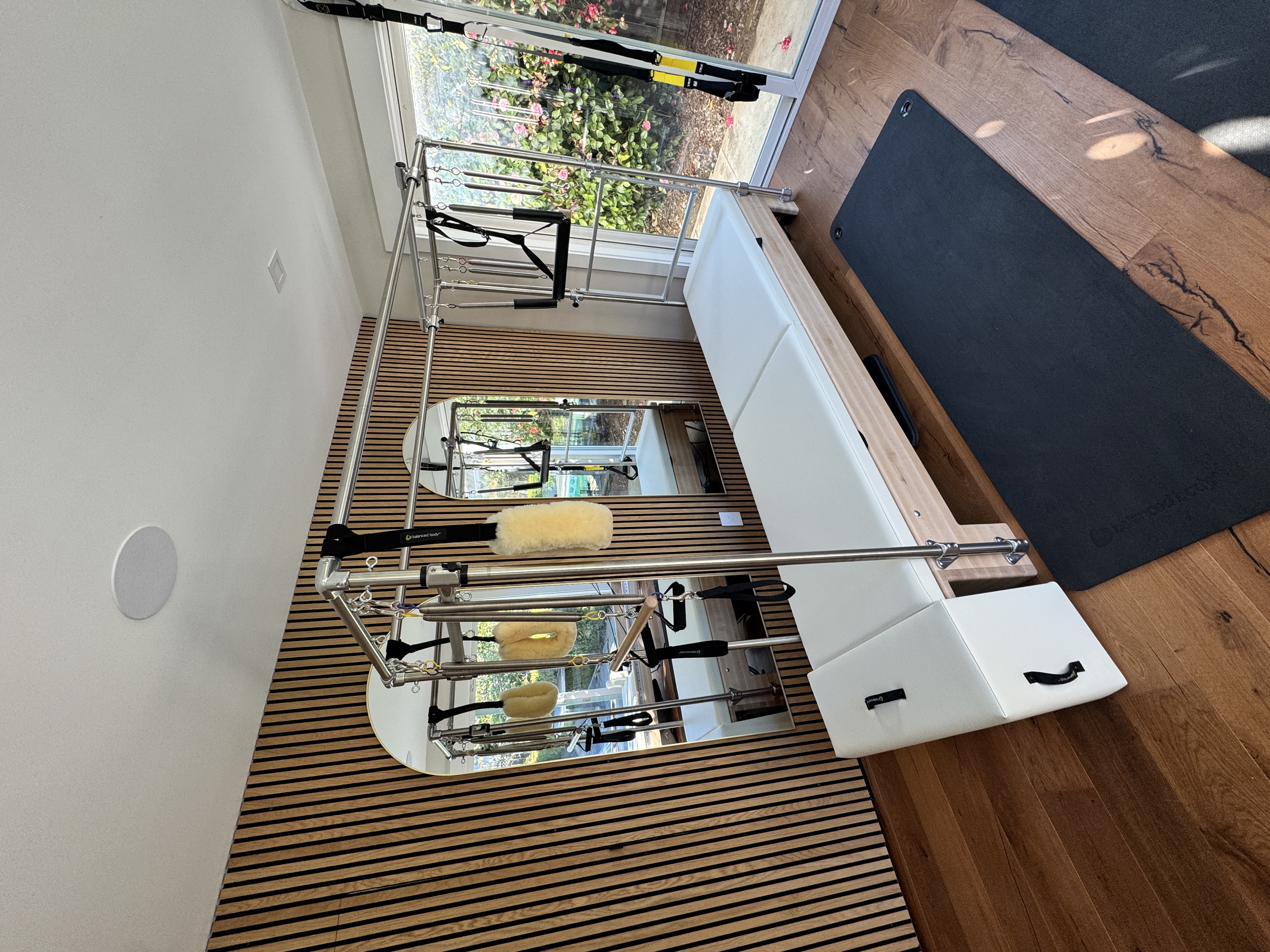 Pilates Cadillac tower apparatus with slatted wood wall and garden window