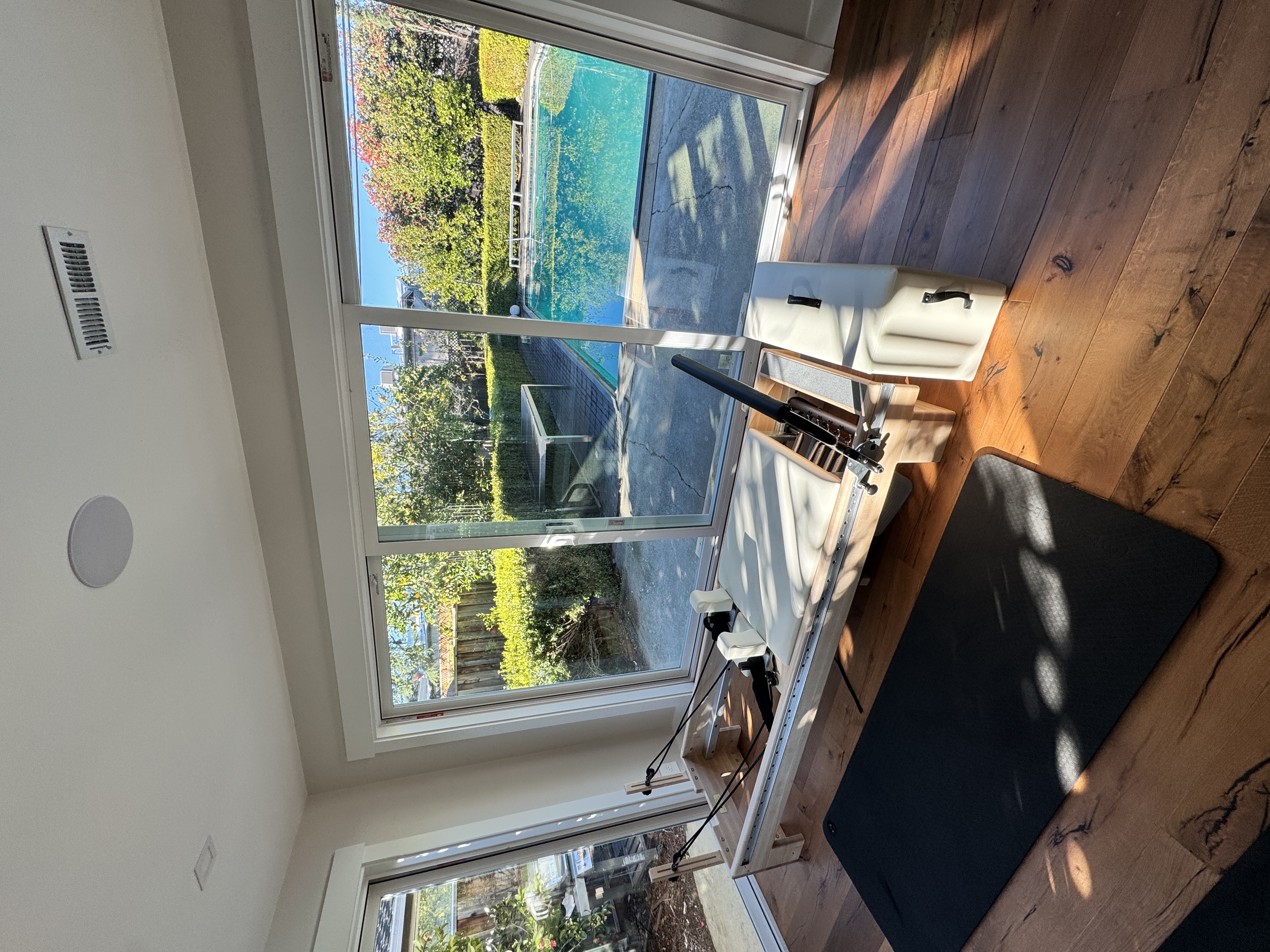 Pilates reformer with poolside garden view through large windows